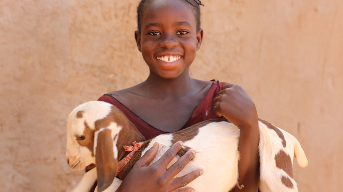 A girl holding a goat and smiling