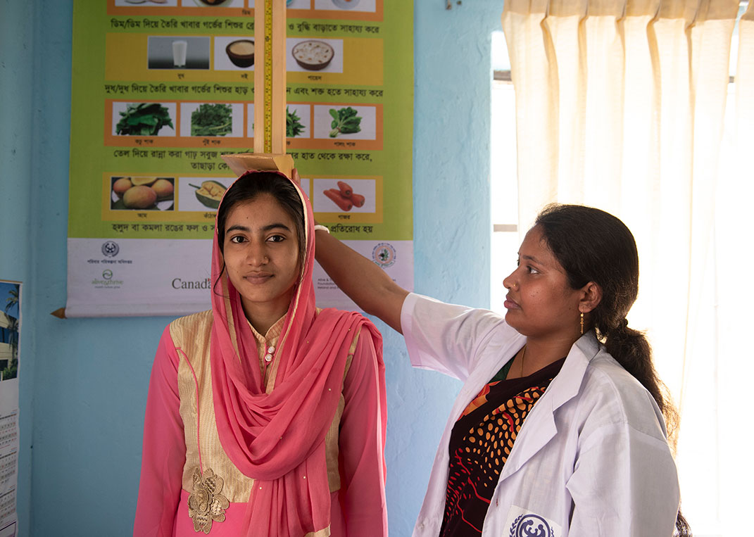 Bithi gets a check-up from a health worker in a Plan International-supported clinic