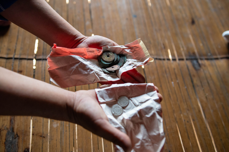 Two hands holding a cloth that contains some old coins