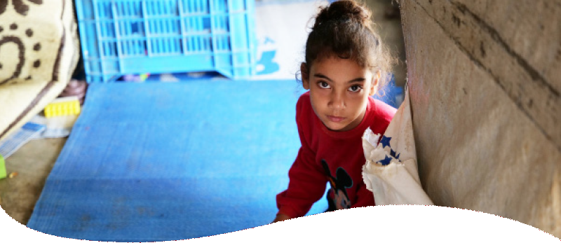 girl looking up from a makeshift shelter