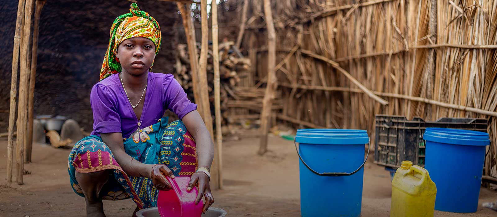 Beti, 15, washes dishes outside the family's shelter
