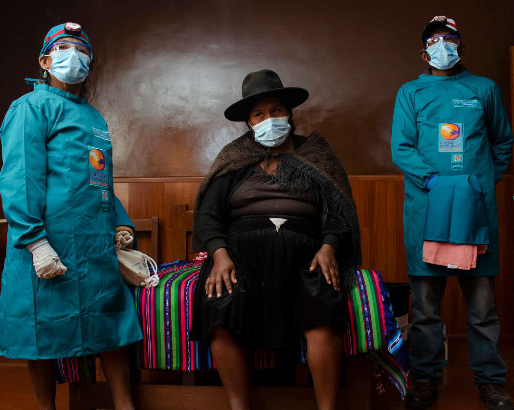 A man and a woman midwife stand beside a pregnant woman in a newly equipped delivery room.