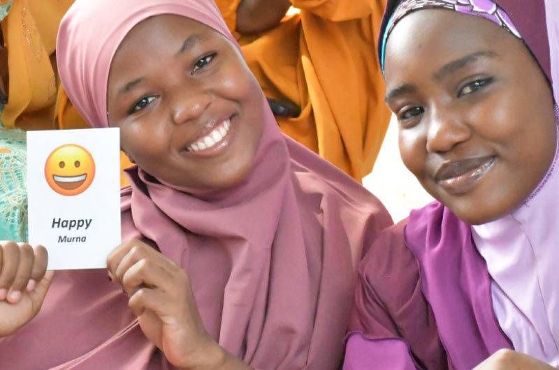 Two young women in pink and purple headscarves participate in a discussion about mental health as part of our ASPIRE project in Nigeria. The project makes health care more accessible for girls and young women and teaches them skills to earn a living.