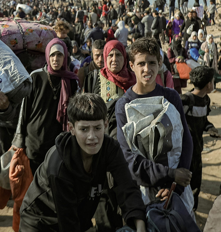 Children and families walk through a crowded area carrying their belongings.  Campaign to raise donations for GAZA EMERGENCY APPEAL.